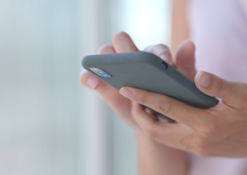Hände halten ein IPhone und tippen etwas mit ihren Fingern darauf
